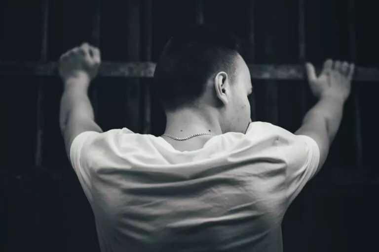 Osoba opierająca się o kraty